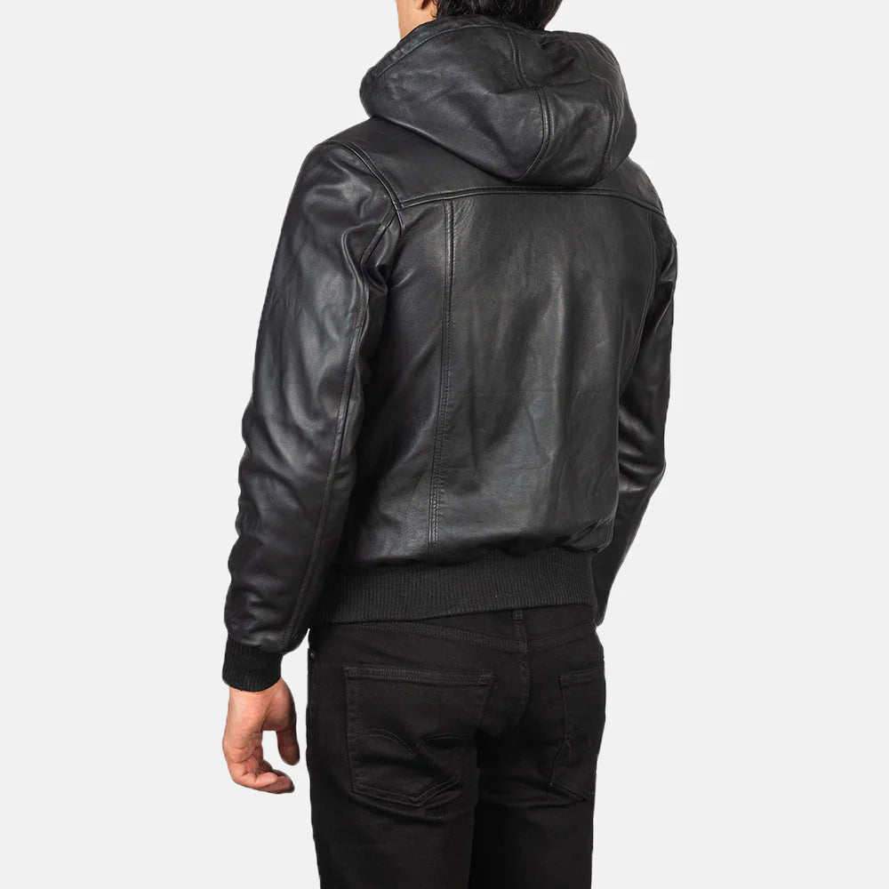 Back view of black hooded leather bomber jacket worn by male model in casual black pants