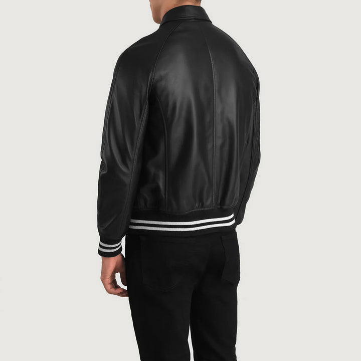 Back view of a man wearing a black leather varsity jacket with striped cuffs and waistband