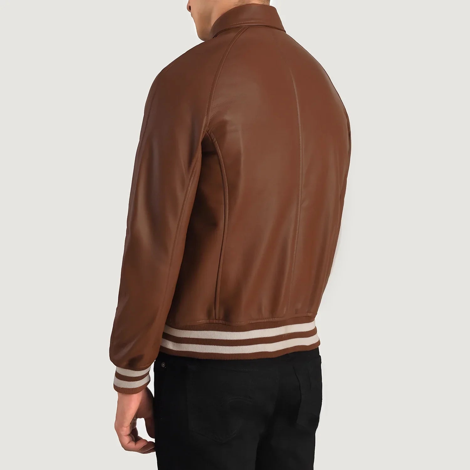 Back view of a man wearing a brown leather varsity jacket with striped cuffs and waistband