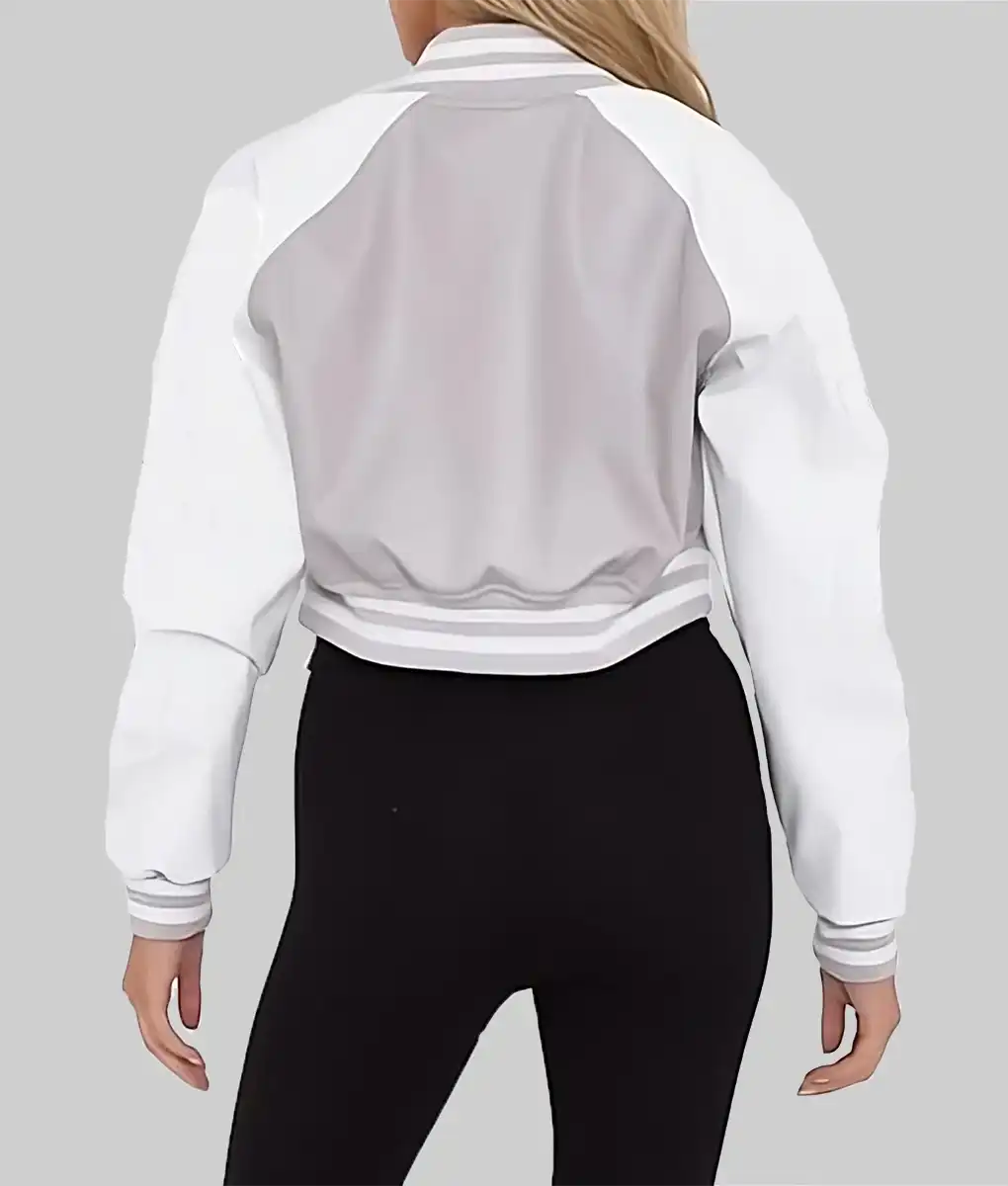 Back view of a women's cropped varsity jacket in white and gray worn with black leggings